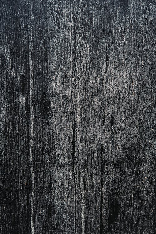 Black and white of textured background of wooden plank with uneven surface and scratches