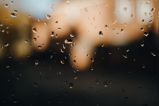 Raindrops on a window, creating a peaceful, blurred cityscape view.
