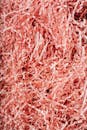 From above heap of shredded crinkled pink paper filler for gift box as abstract background
