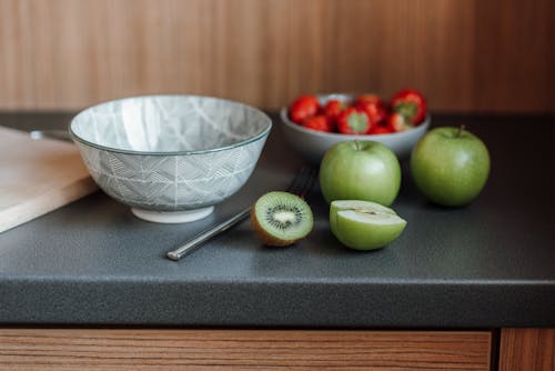 Kitchen counter with fruits and berries near dish and fork