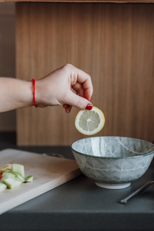 Crop woman preparing healthy fruit salad from lemon and apples