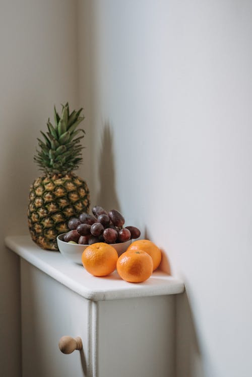 Tropical fresh fruit and grapes on cabinet in room