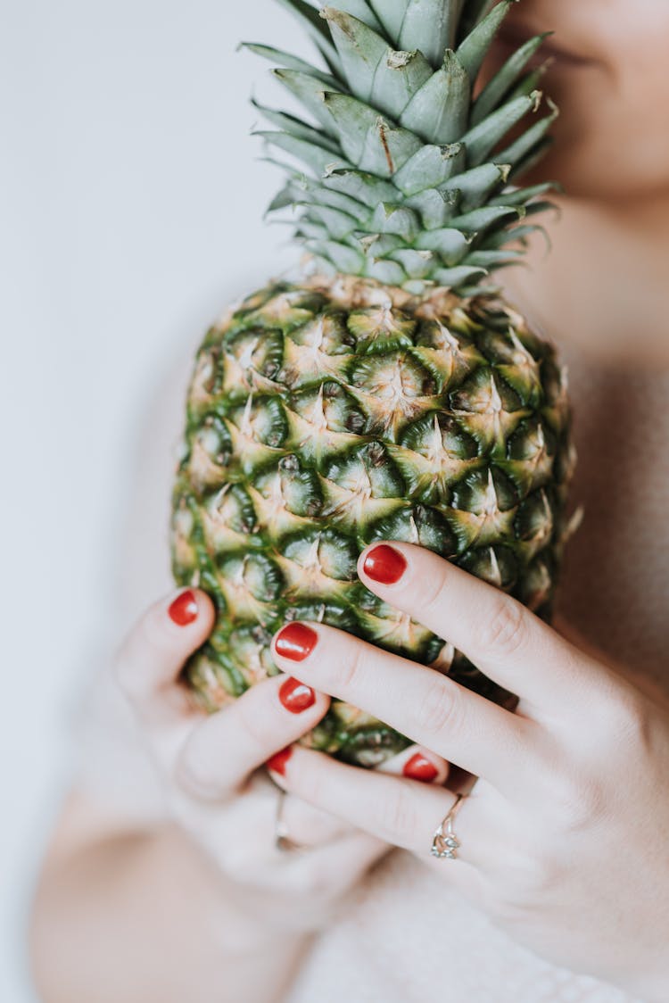 Woman Smelling Aroma Of Big Pineapple