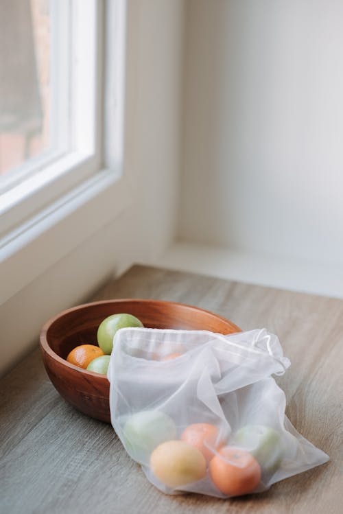 Fruit in bag and bowl on windowsill