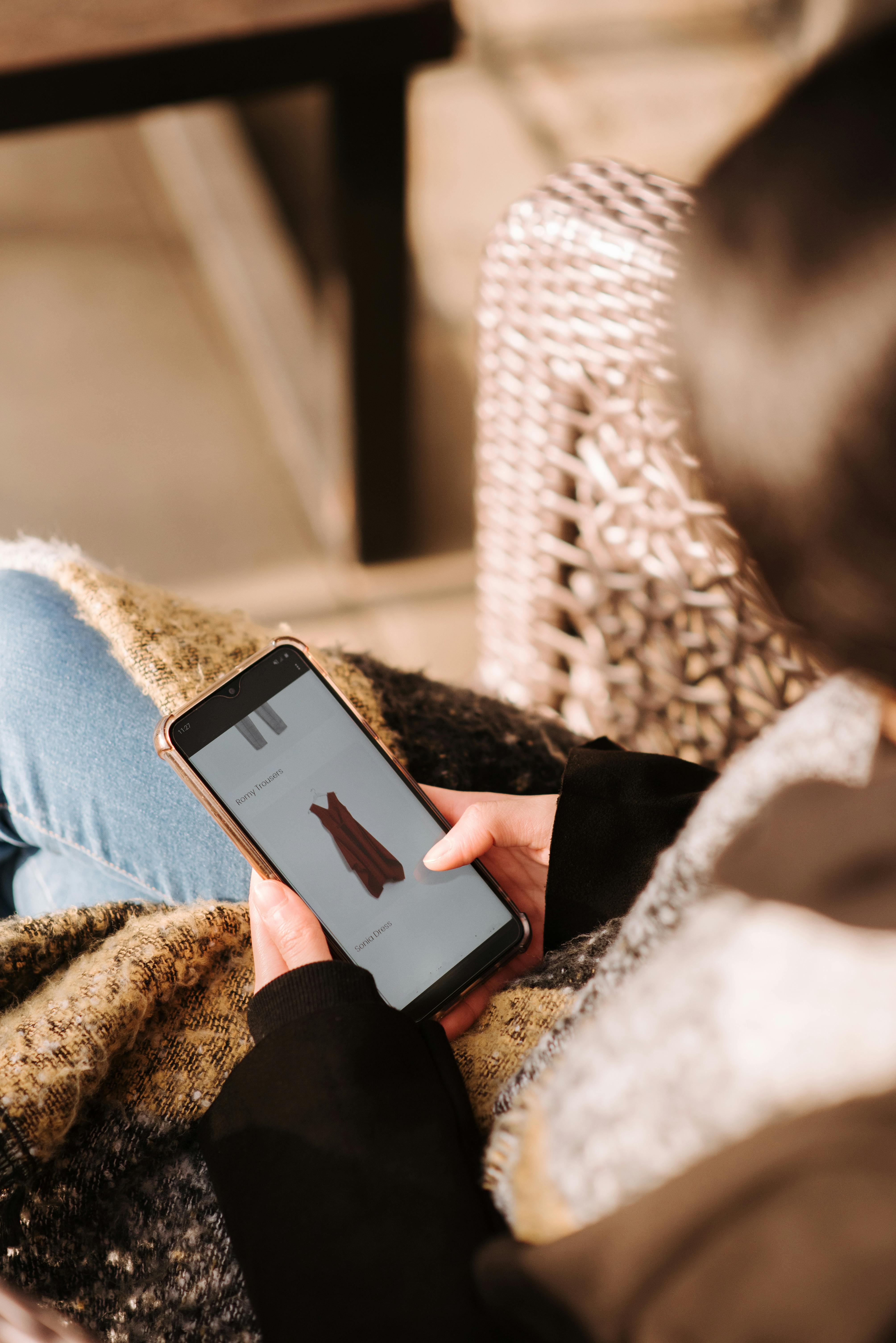 woman using smartphone for online shopping sitting in armchair