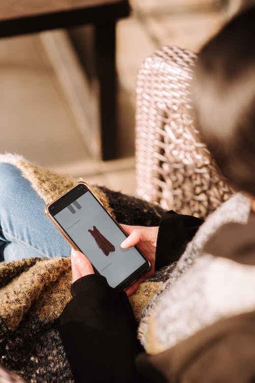 Woman using smartphone for online shopping sitting in armchair