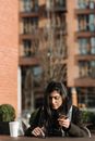 Hispanic purchaser with smartphone shopping online in city cafe
