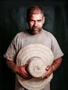Photograph of a Man Holding His Sunhat while Looking at the Camera