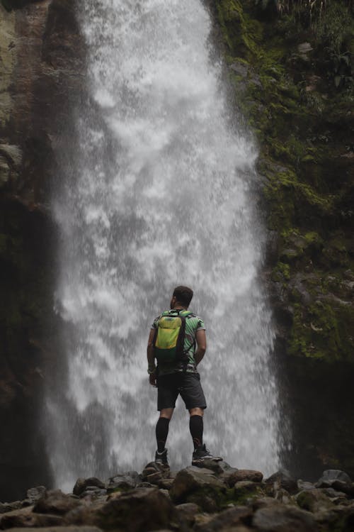 Man In Groen Shirt En Zwarte Korte Broek Met Rugzak Staande Voor Watervallen