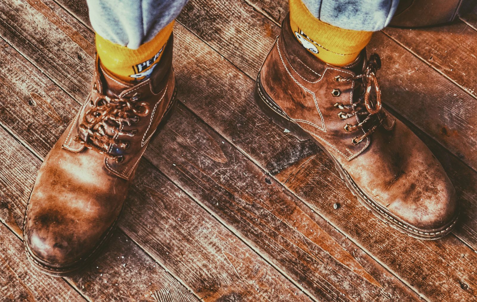 Worn brown leather boots on a wooden floor