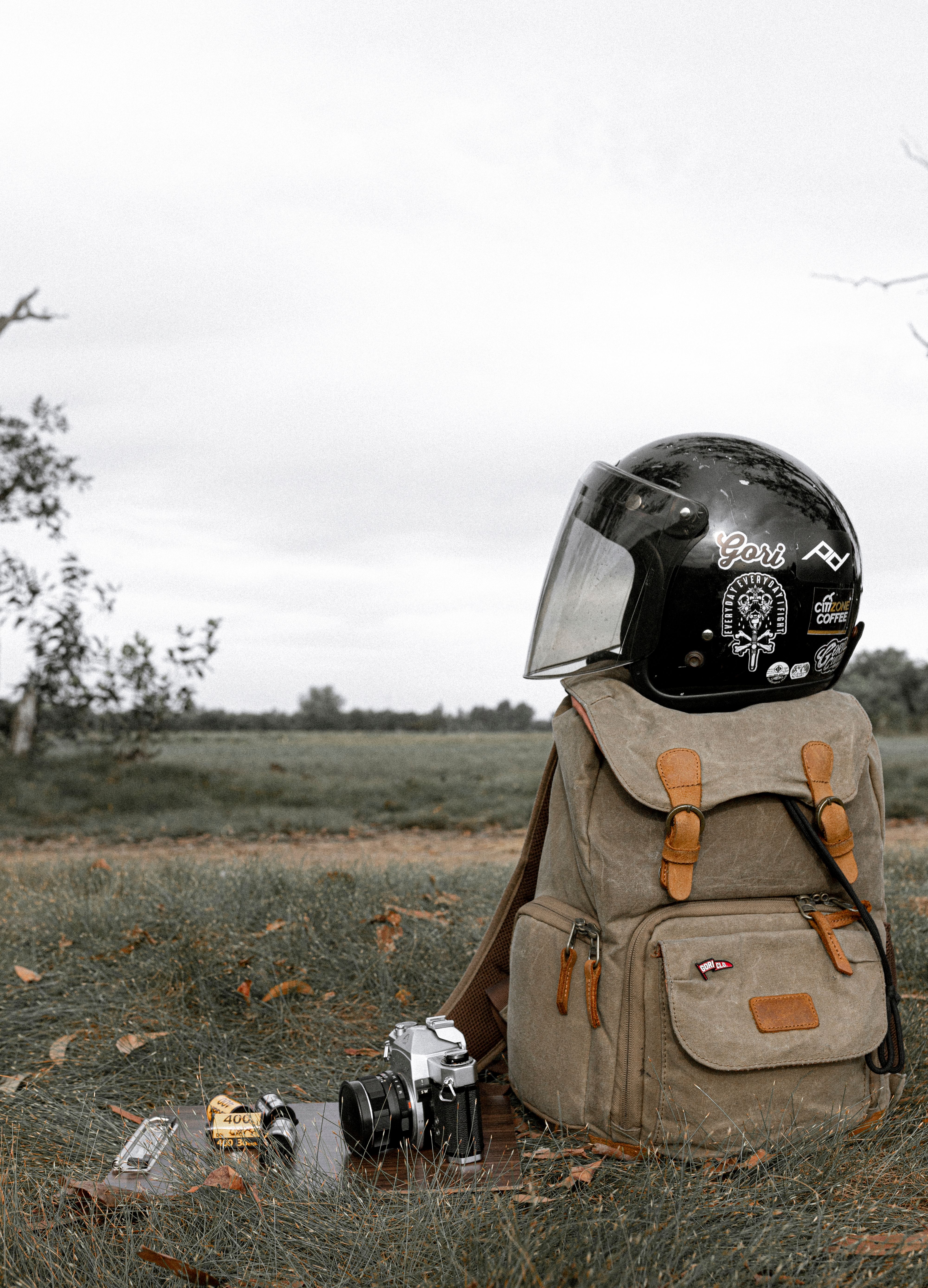 Traveler rucksack with motorcycle helmet on grassy field