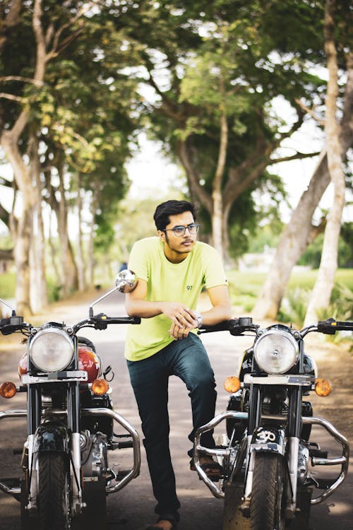 Photo of a Man Posing Between Two Motorcycles