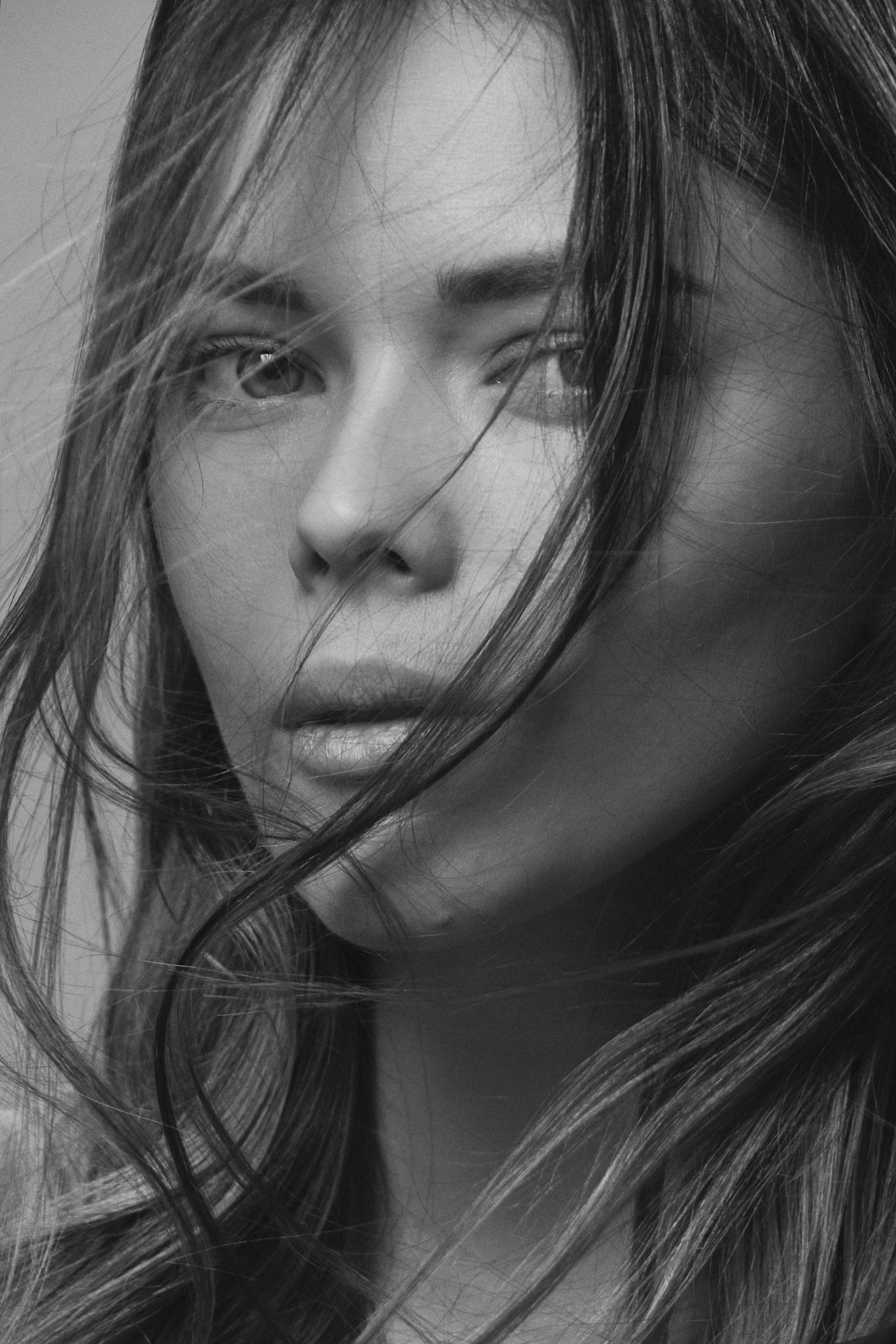 Grayscale close-up of a young woman with flowing hair, evoking emotion and depth.