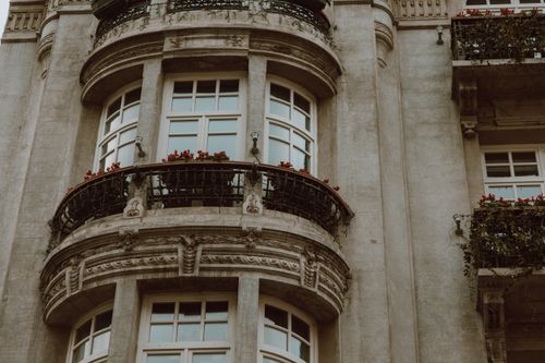 Free Elegant vintage facade featuring ornate balconies and flower-adorned windows. Stock Photo