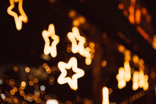 Free Star-shaped bokeh lights creating a warm and festive nighttime atmosphere. Stock Photo