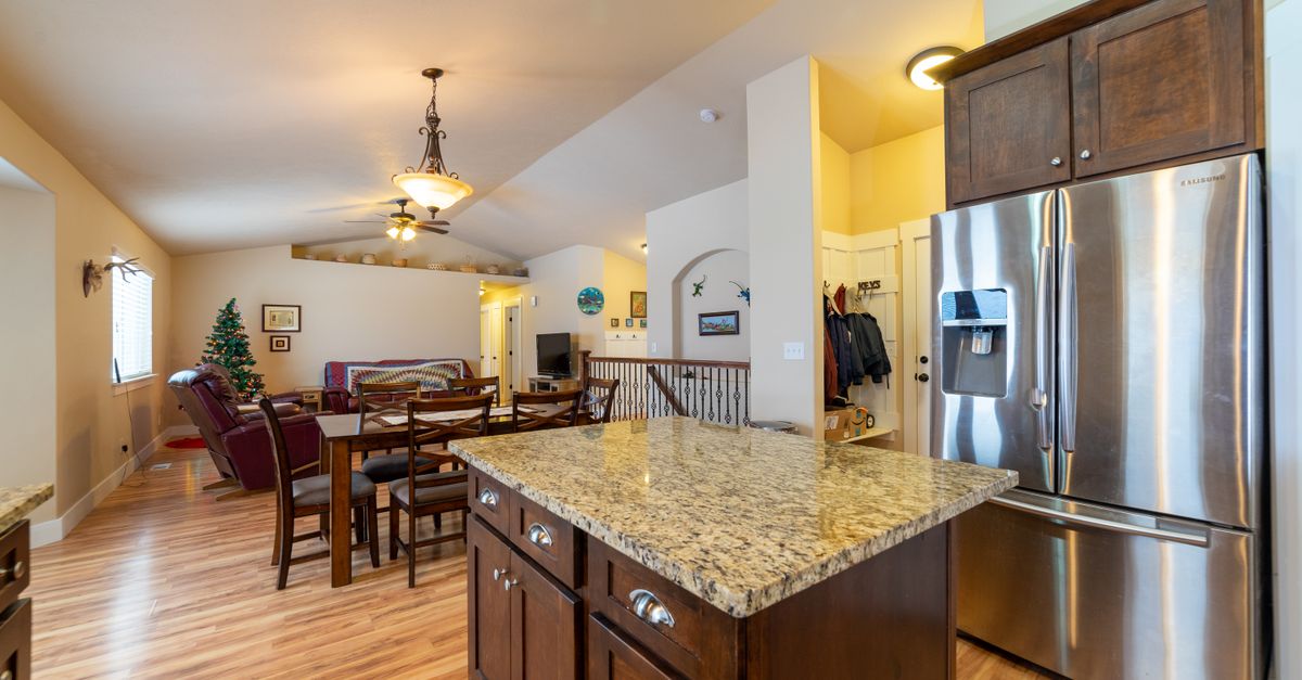 Contemporary home interior featuring a granite kitchen island and open dining room with elegant lighting.