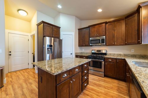 Free Spacious kitchen featuring wooden cabinets, granite countertops, and stainless steel appliances. Stock Photo