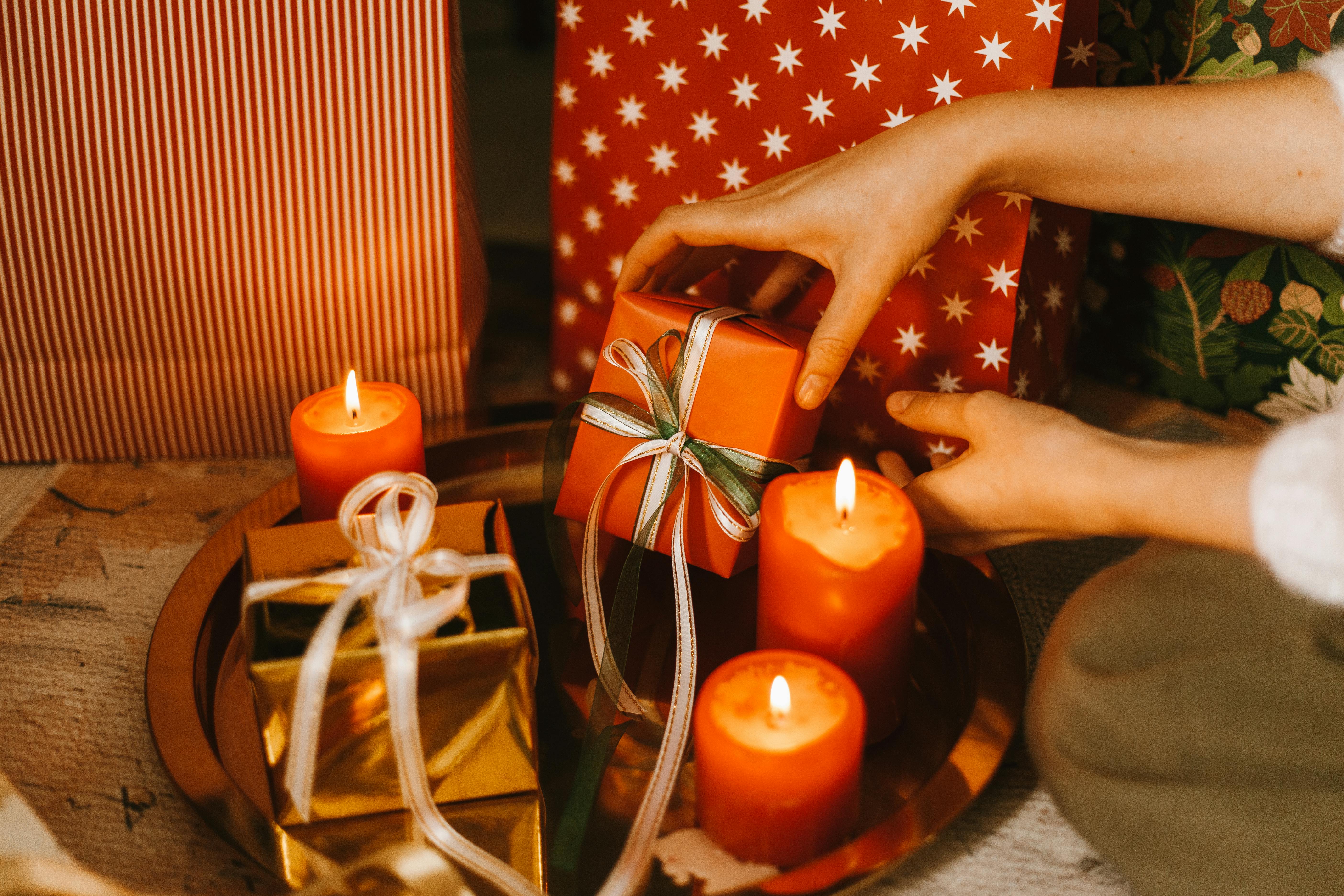 a person placing gifts beside the candles