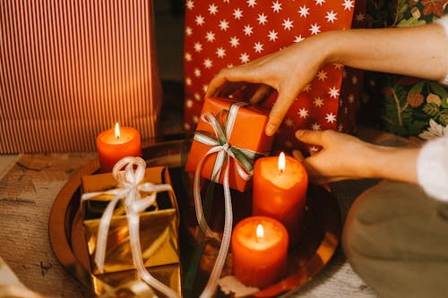 A Person Placing Gifts Beside the Candles