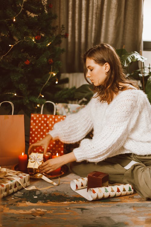 Free A Woman Wearing a Knitted Sweater Wrapping Christmas Gifts Stock Photo