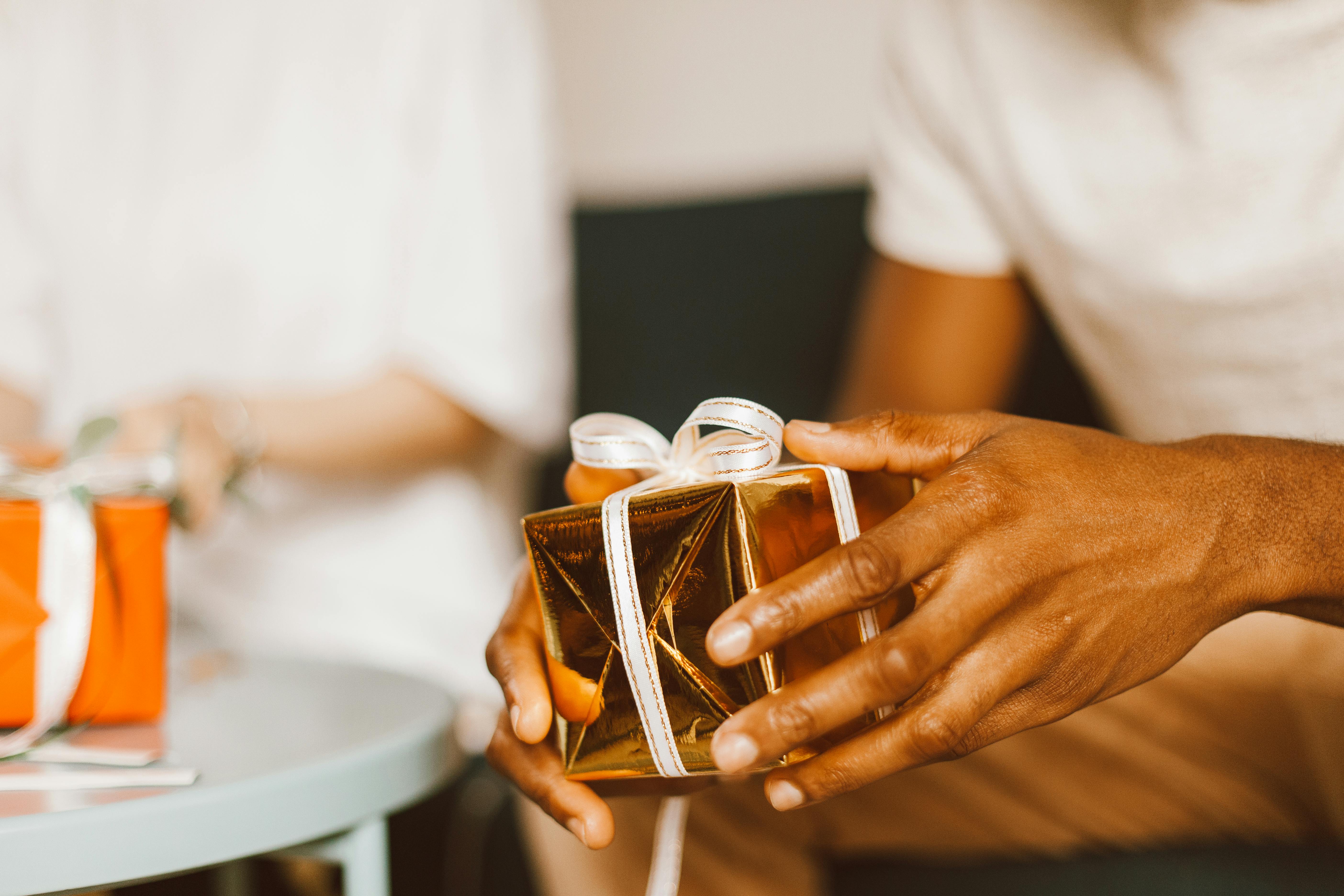 a person holding a gold gift box