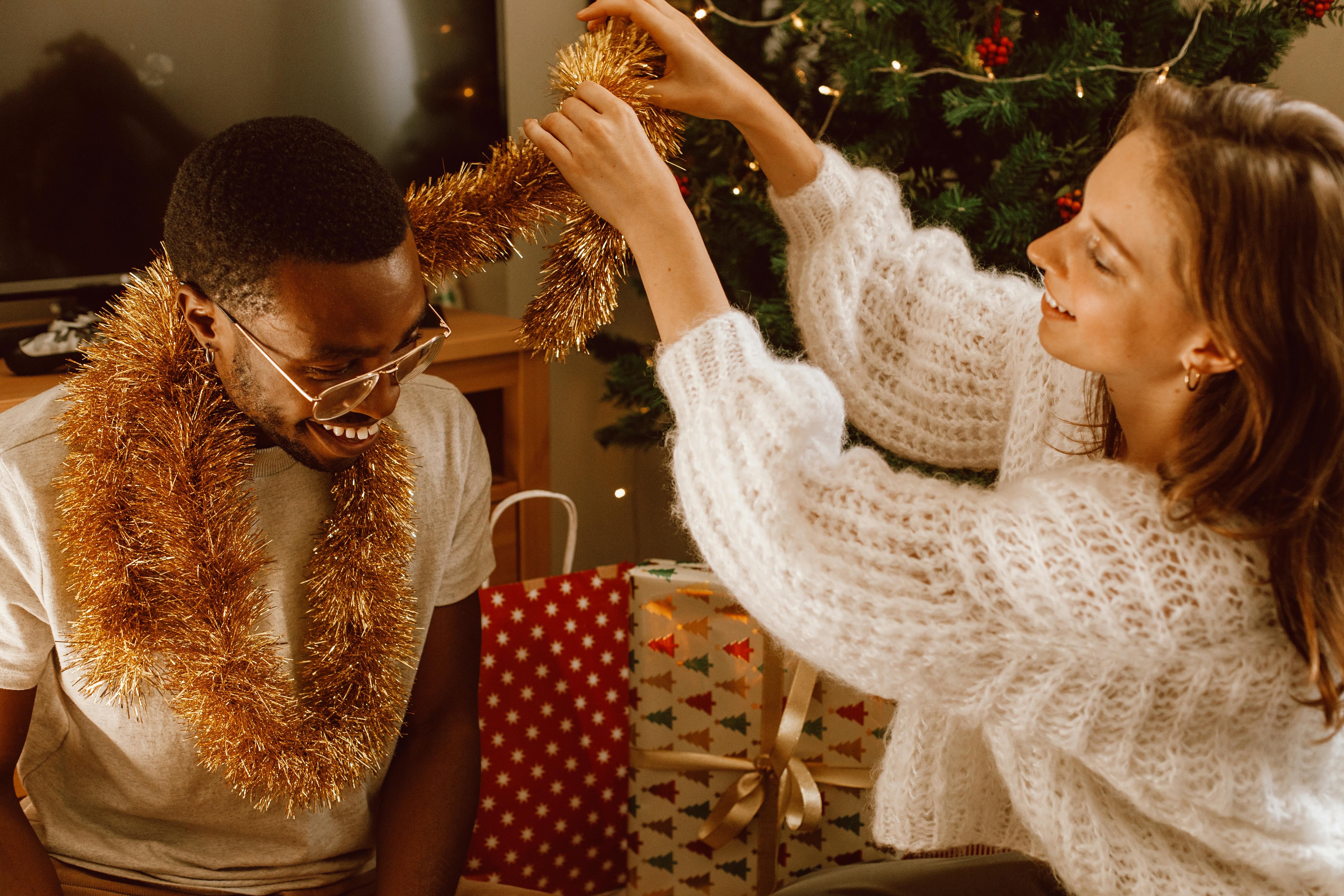 a woman wrapping a garland to man s neck