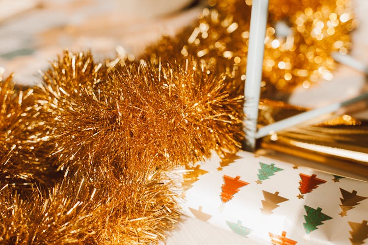 A Gold Garland Lying Over A Christmas Gift Wrapper