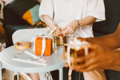 Free Individuals wrapping gifts, focusing on hands and packages on a table indoors. Stock Photo