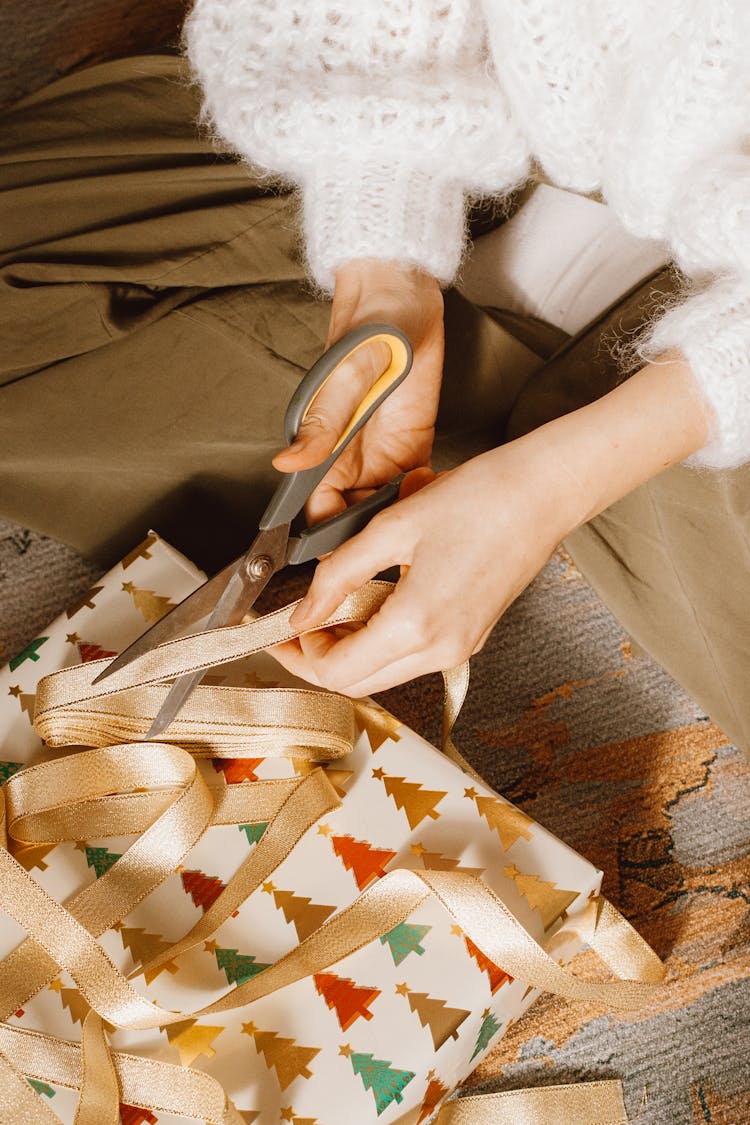 A Person Holding Scissors While Cutting The Ribbon