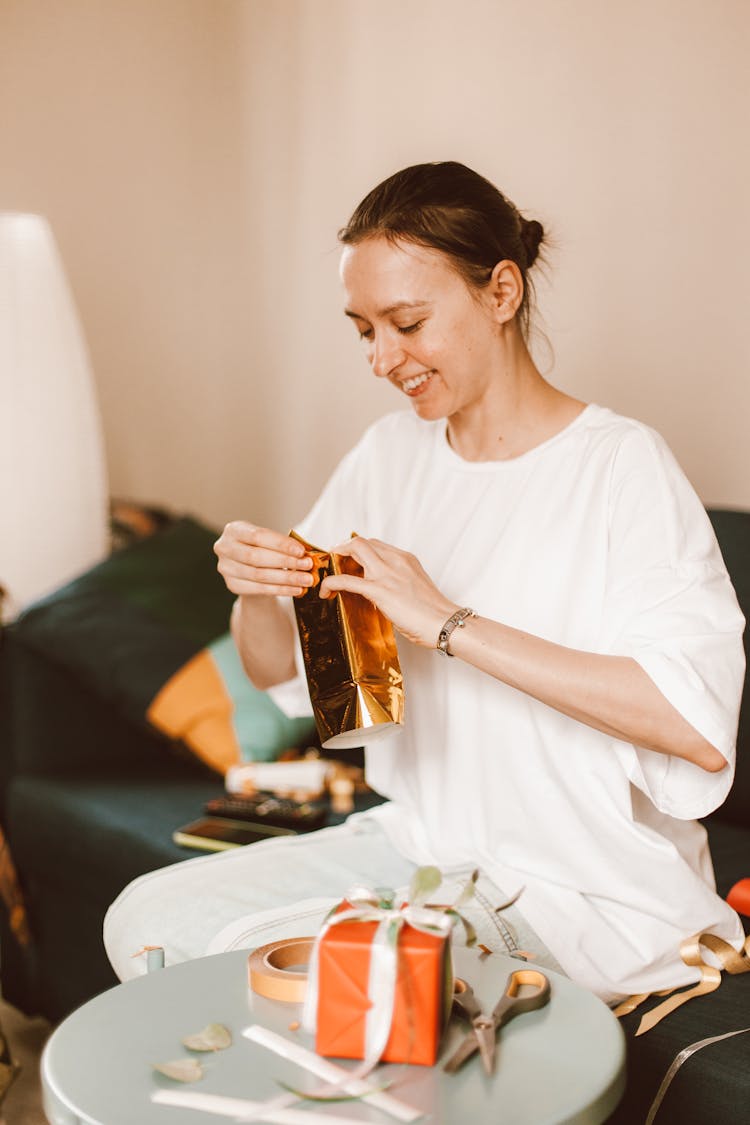 A Woman In White Shirt Holding A Gold Object