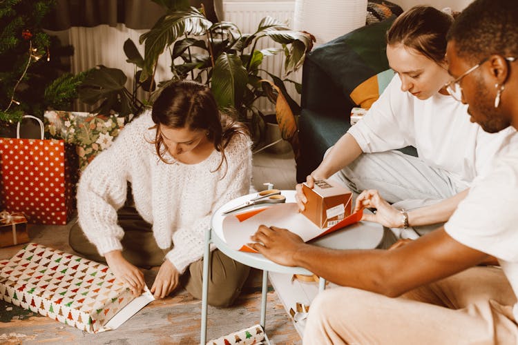 A Group Of Friends Helping Each Other While Wrapping Gifts