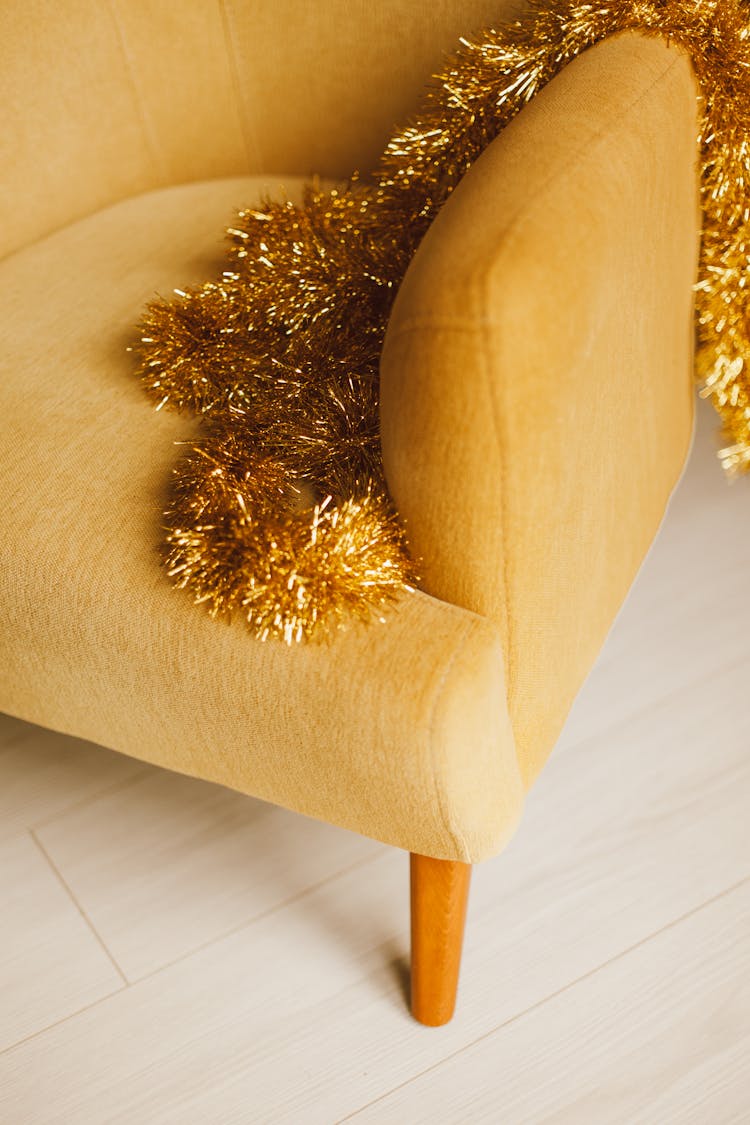 Golden Christmas Tree Decoration Lying On Yellow Chair