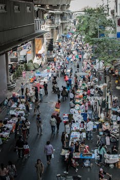 High angle view of a lively street market filled with people and stalls in an urban setting.