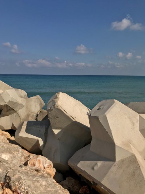 Free Concrete tetrapods on a rocky shore with clear blue sea on a sunny day. Stock Photo