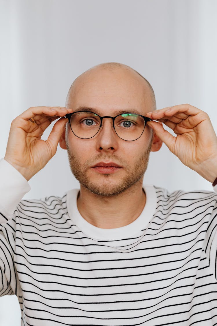 Man Holding Temples Of Eyeglasses