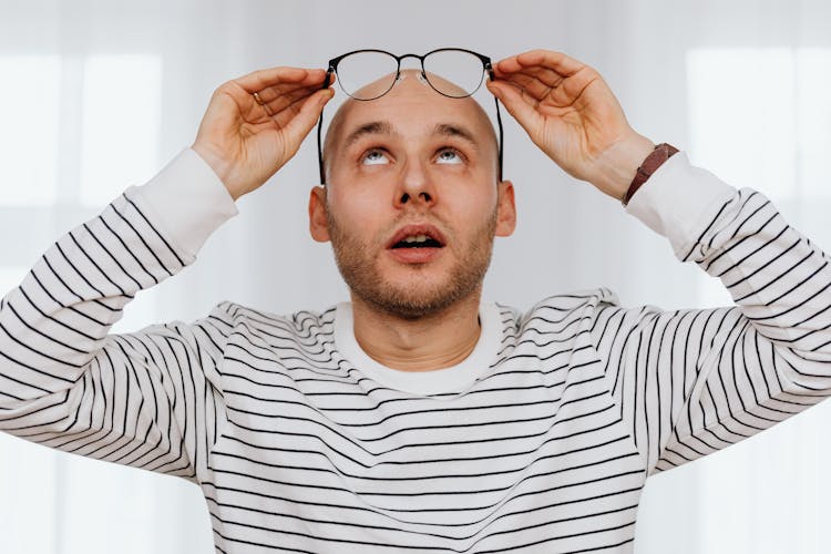 Man Looking At Eyeglasses While Taking It Off 