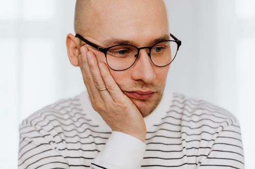 Free Close-up of a pensive man with glasses in a striped shirt. Mental health concept. Stock Photo