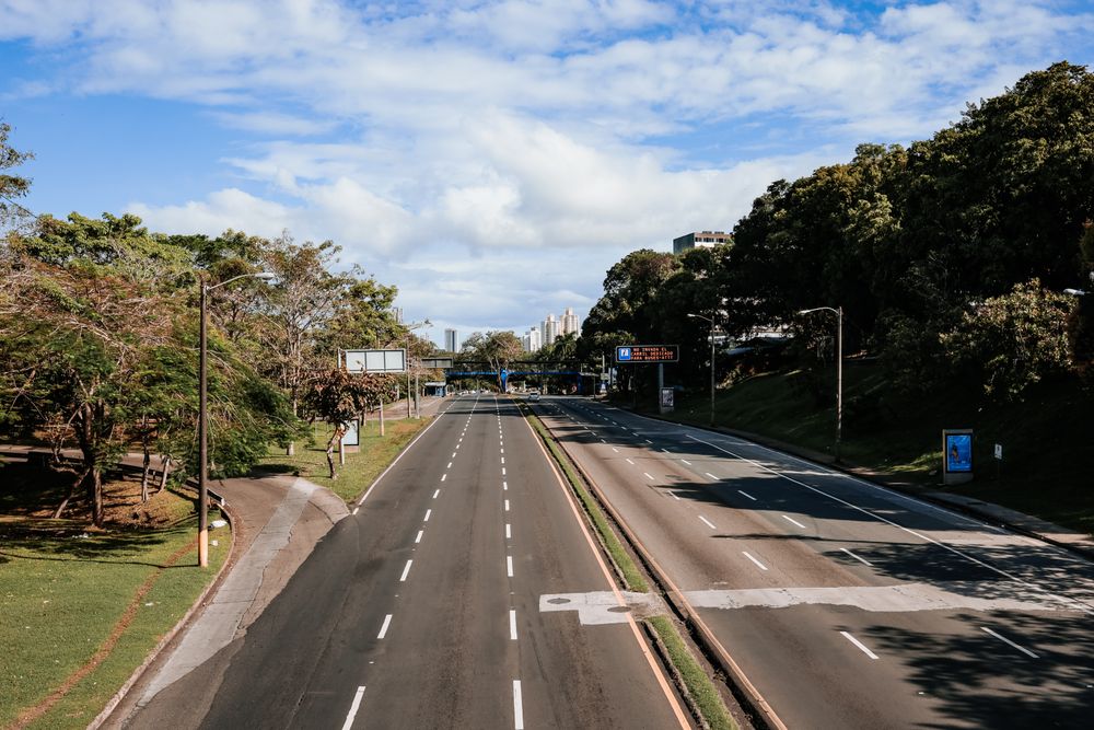 Autostradă goală printre zone verzi, sub cerul senin