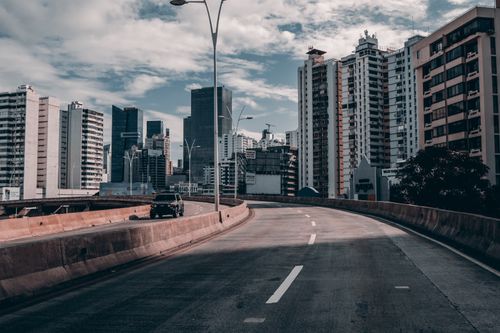Free A city expressway curves into a skyline with modern skyscrapers under a cloudy sky. Stock Photo