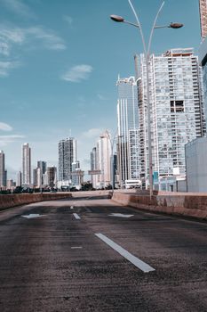 A clear city highway with towering skyscrapers under a blue sky, offering an urban transportation view.