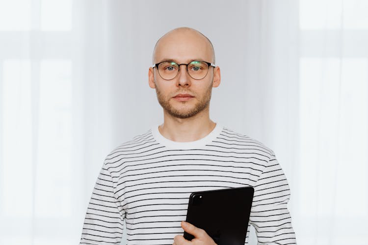 A Bald Man In Striped Shirt Holding An Ipad