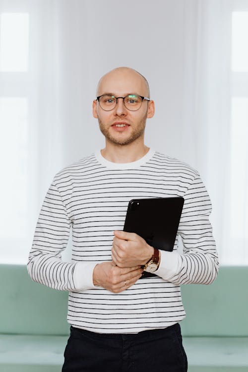 Free A Bald Man in Striped Shirt Holding an Ipad Stock Photo