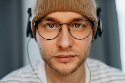 Close-Up Shot of a Man Wearing an Eyeglasses and Brown Bonnet