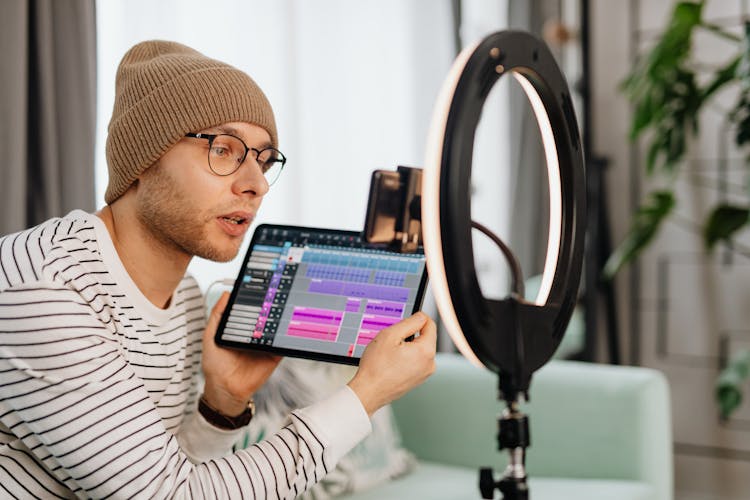 A Man Holding A Tablet Recording Video Using Smartphone