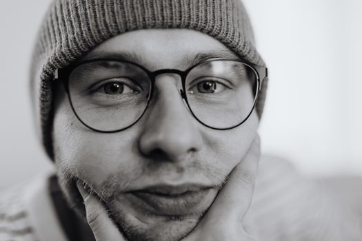A thoughtful monochrome portrait of a man wearing glasses and a beanie.