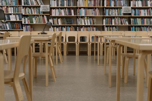 Sleek library interior showcasing rows of books and minimalist wooden furniture.