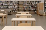 Spacious library interior with wooden tables and shelves packed with books.