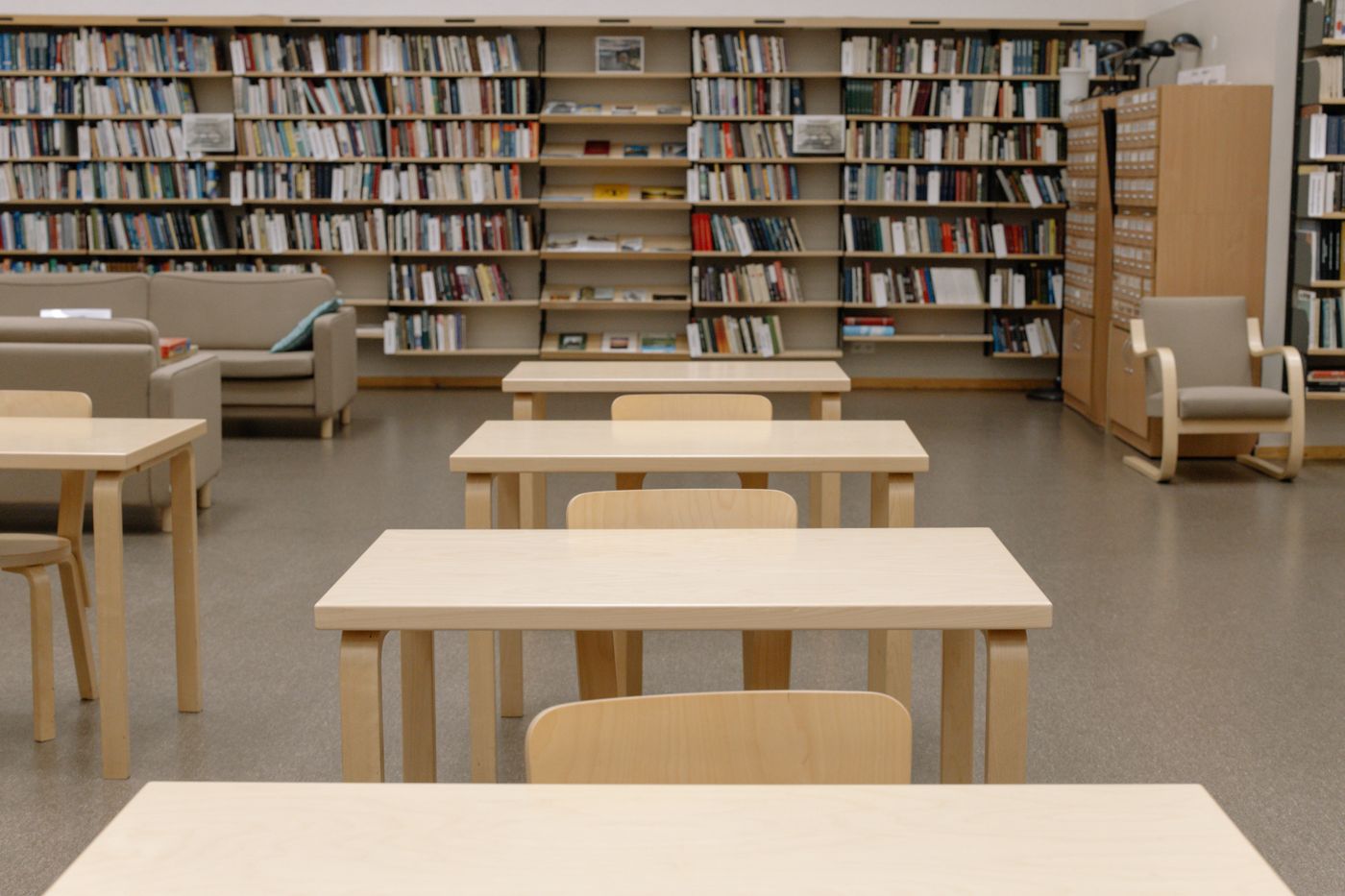 Reading room with long wooden tables and full shelves — photo by cottonbro studio on Pexels