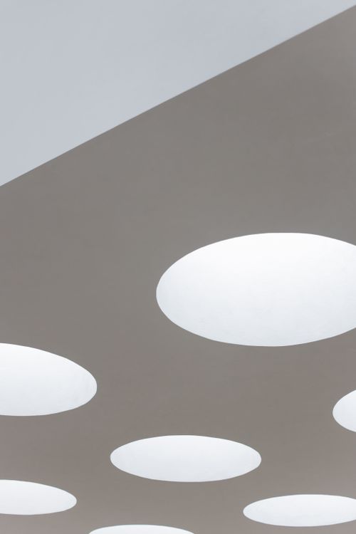 Free A modern ceiling design featuring round recessed lighting fixtures, creating a minimalist look. Stock Photo