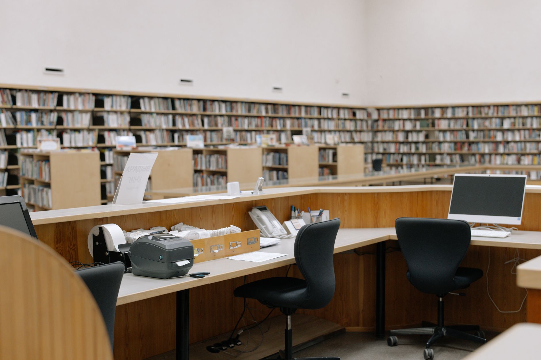 Interior view of a university library with bookshelves and computer workstations.